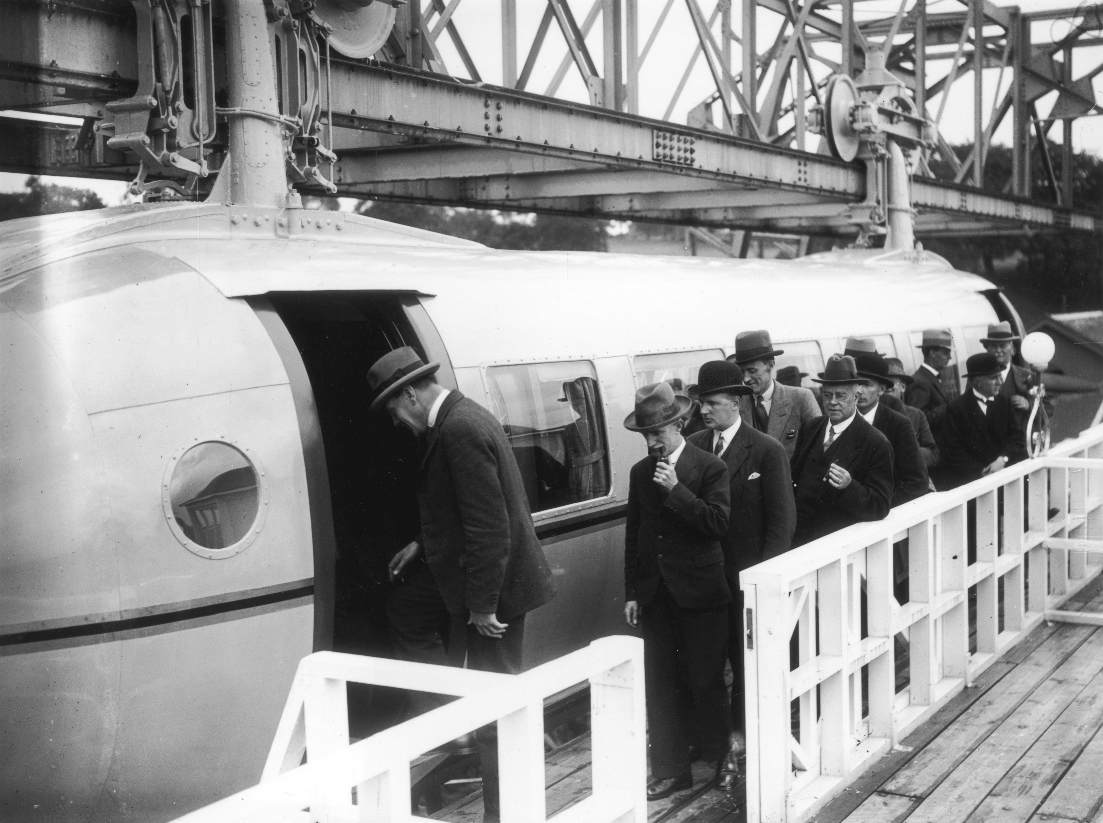 4th July 1930: The first load of passengers queuing for the Bennie Railplane in Glasgow; the inventor George Bennie is third in the queue. The streamlined cars are self propelled, driven by air screws in front and behind, and hang from a steel girder. (Photo by J. A. Hampton/Topical Press Agency/Getty Images)